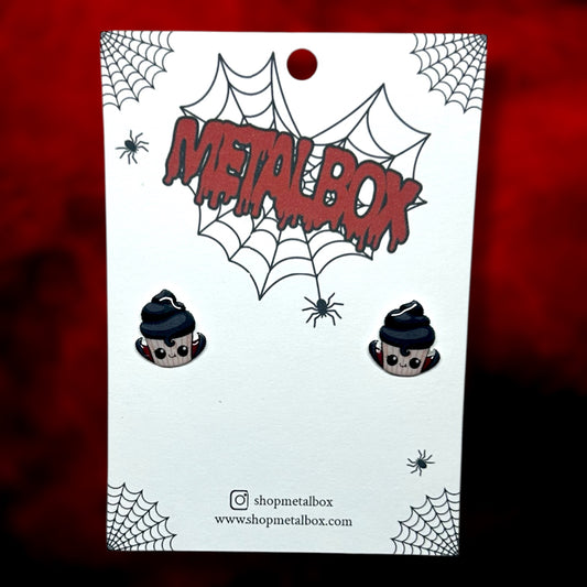 Vampire cupcake stud earrings on a blurred red and black background.