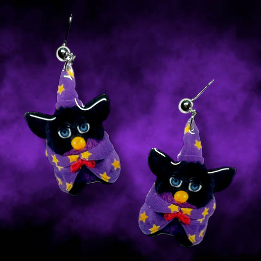 Earrings of a classic Furby dressed as a wizard with a wizard hat and cape on a smoky purple background.