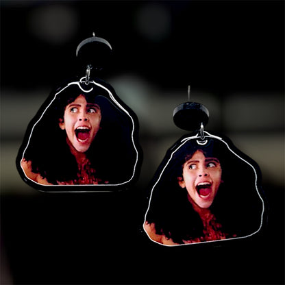 Sleepaway Camp bloody Angela screaming resin horror dangle earrings on a blurry background