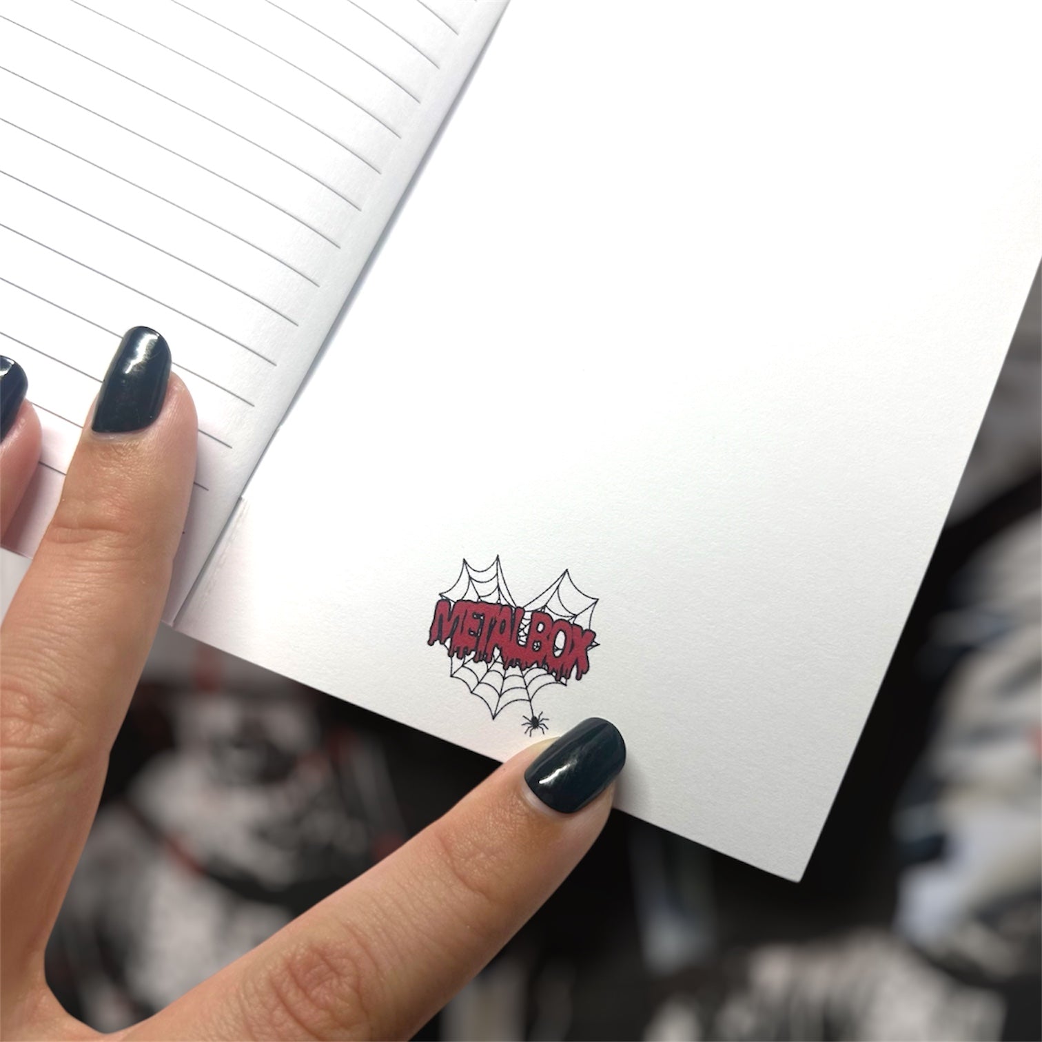 Metalbox logo inside the back cover of a pocket notebook on a blurry background