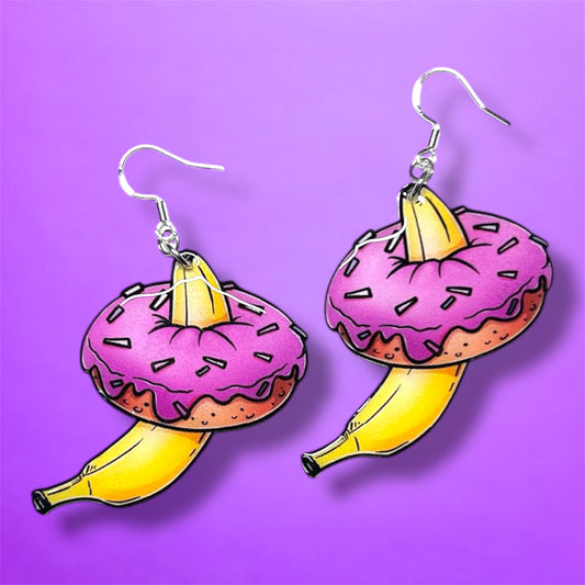 Banana inside pink sprinkle donut resin dangle earrings on a purple background