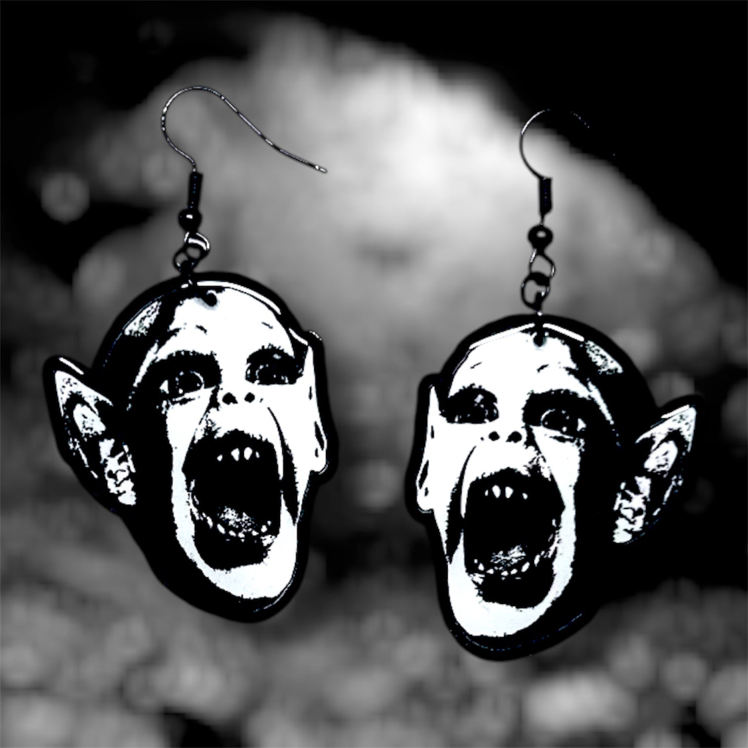 Bat boy spooky resin dangle earrings on a blurry black and white background