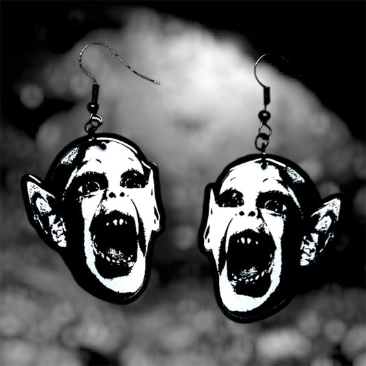 Bat boy spooky resin dangle earrings on a blurry black and white background