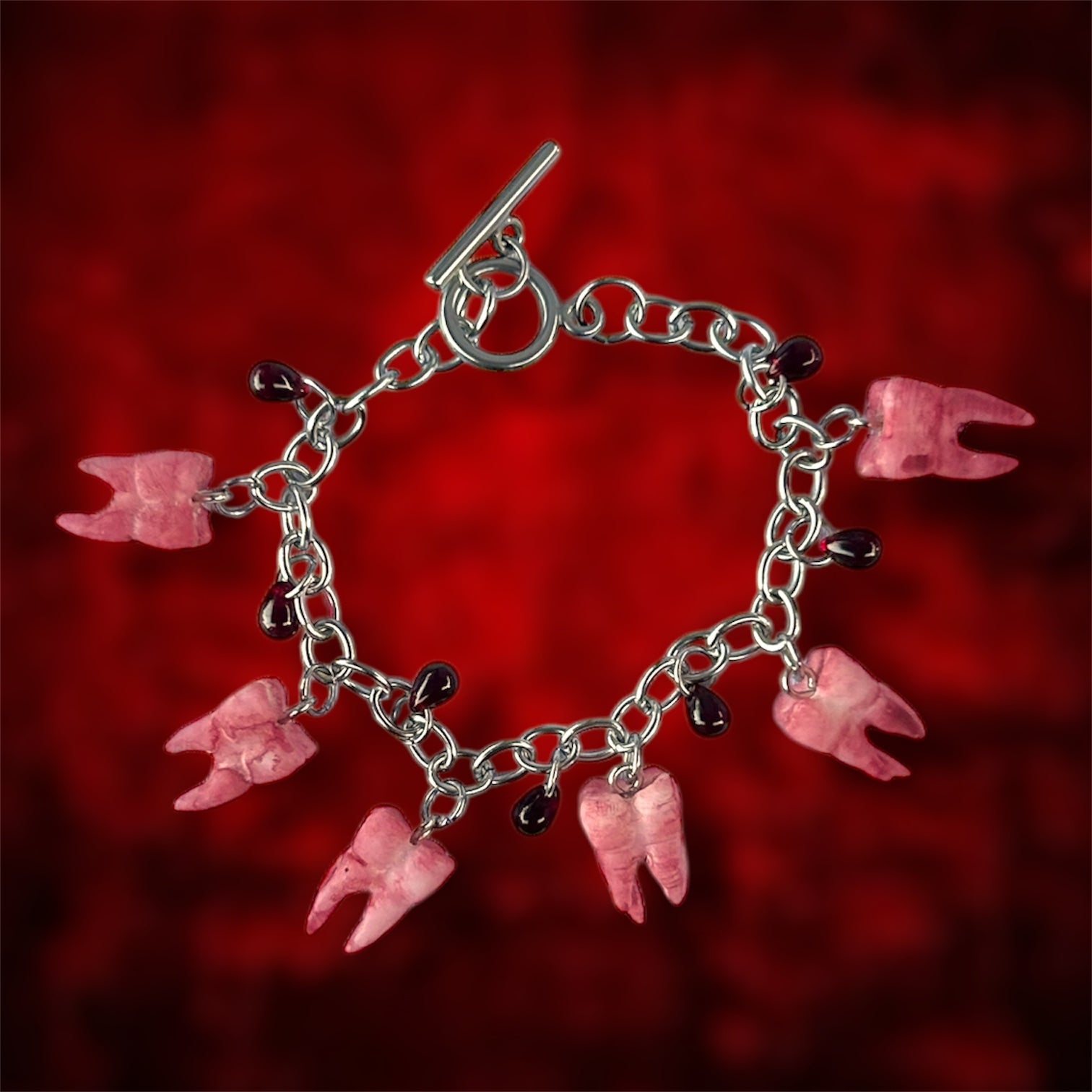 Bloody molars and blood drops charm bracelet on a blurred red background