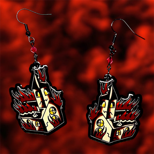 Burning church resin dangle earrings with red glass beads and black earring hooks on a blurry red background