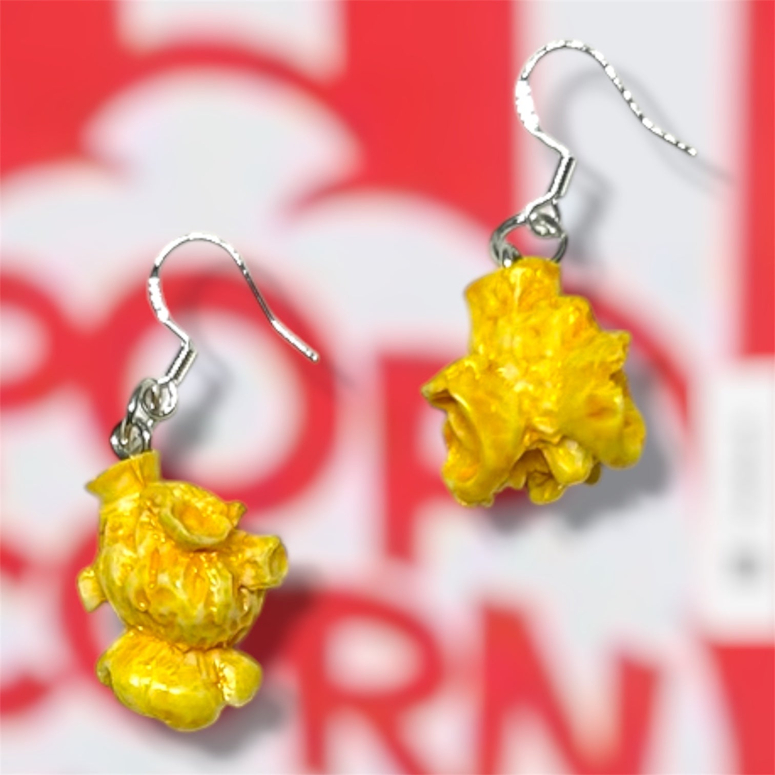Buttered popcorn dangle earrings on a red and white popcorn bucket background