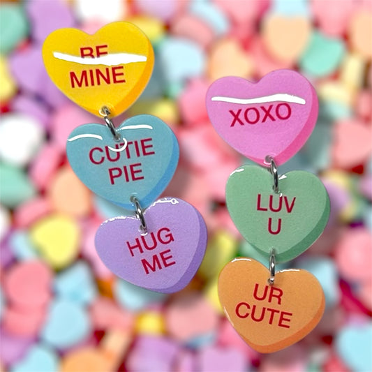 Valentine's Day Sweethearts conversation hearts stacked dangle earrings on a blurred colorful background