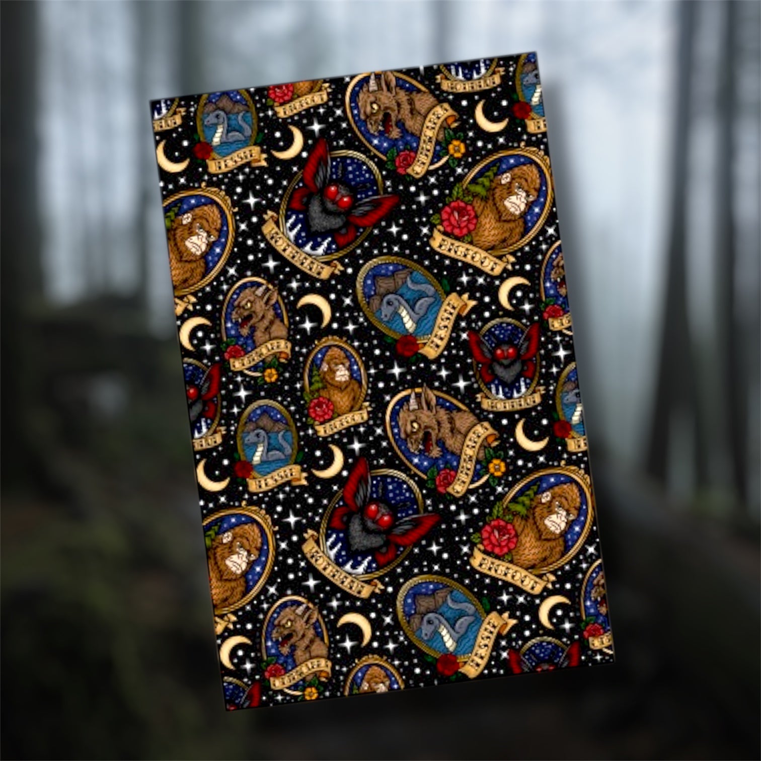 Framed cryptid art pocket notebook, featuring the Chupacabra, Mothman, Bigfoot, and the Loch Ness monster, with traditional style flowers on a blurry forest background