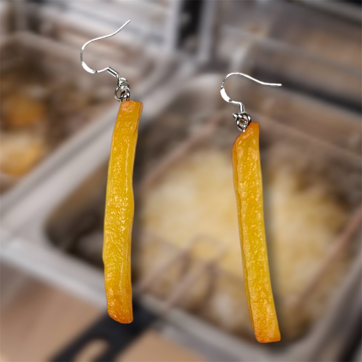 Realistic French fry dangle earrings on a blurry background