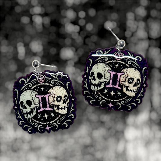 Gemini zodiac sign twin skulls witchy resin dangle earrings on a blurry black and white background