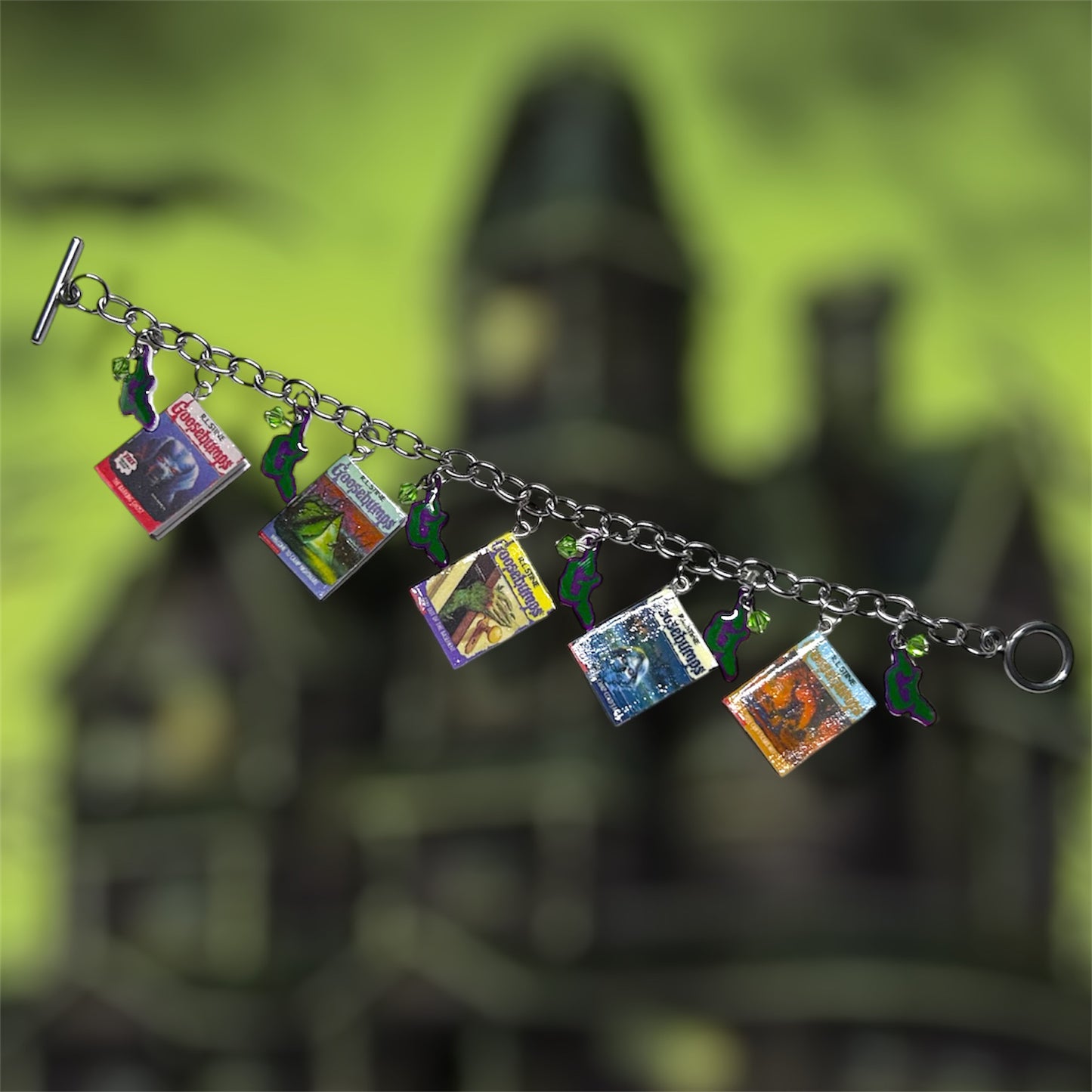 Classic Goosebumps miniature books nostalgic horror charm bracelet on a blurry green background