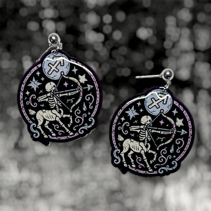 Sagittarius zodiac sign centaur with bow and arrow resin dangle earrings on a blurry black and white background
