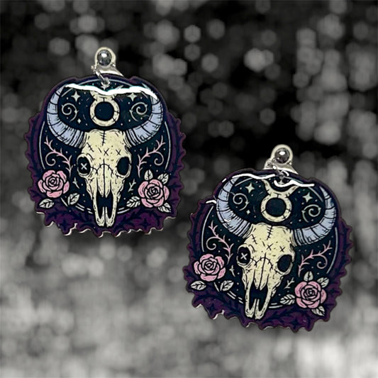 Taurus zodiac sign skeleton floral bull skull dangle earrings on a blurry black and white background