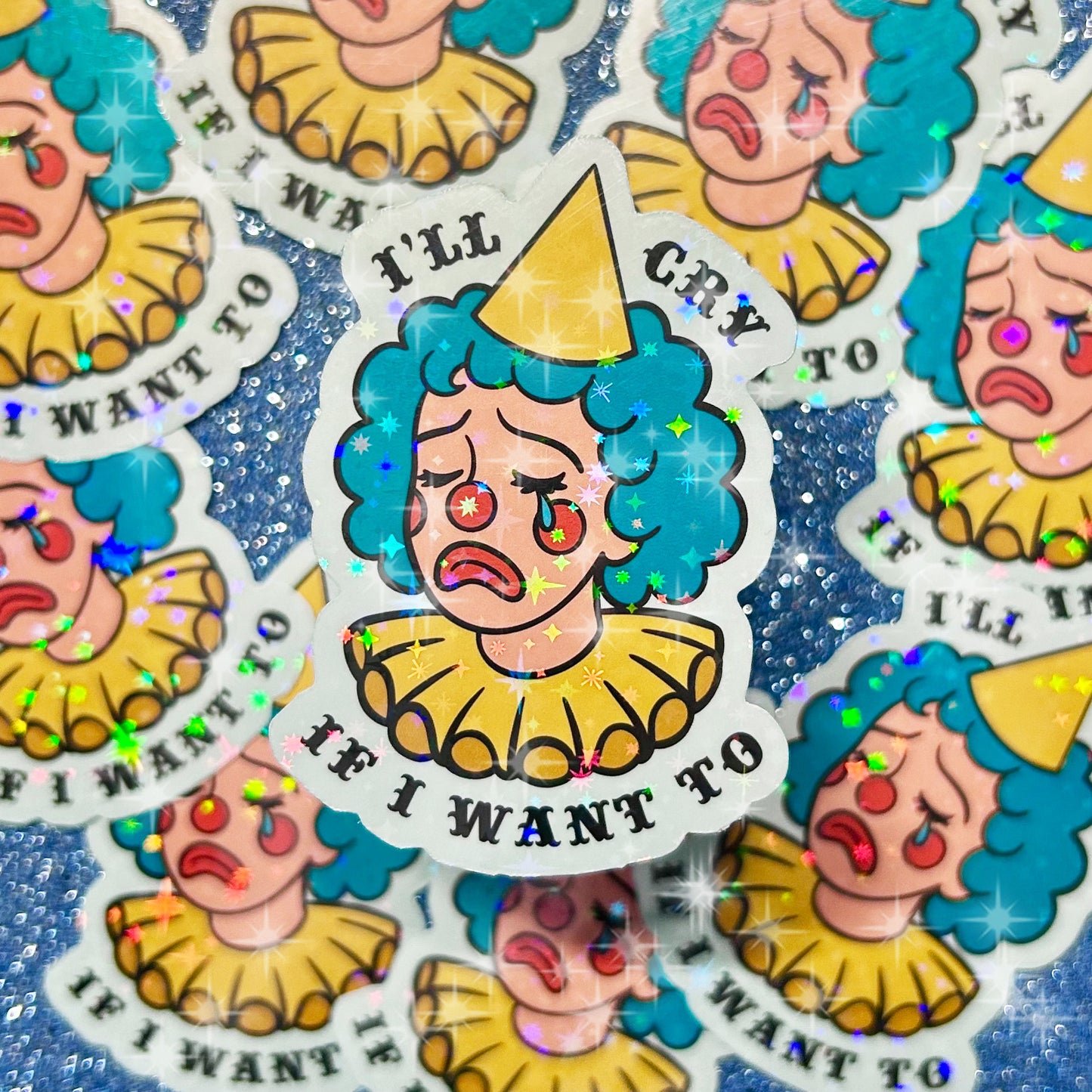 Holographic sparkly stickers of a blue and yellow crying clown lady with text that reads "I'll cry if I want to" on a glittery blue background