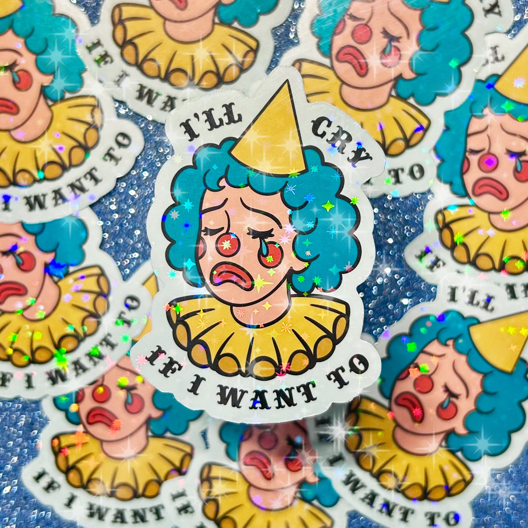 Holographic sparkly stickers of a blue and yellow crying clown lady with text that reads "I'll cry if I want to" on a glittery blue background