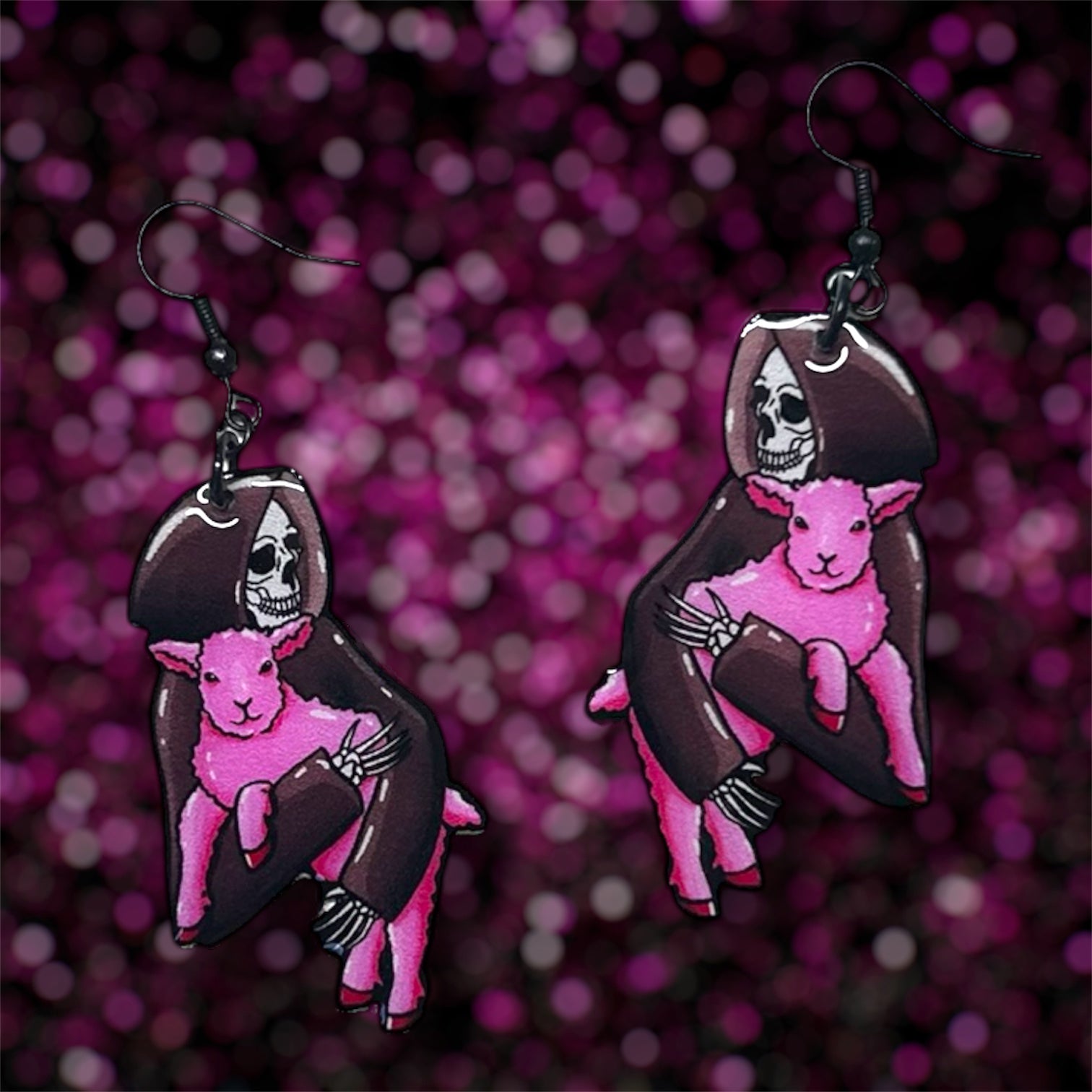 A pair of earrings of a Grim Reaper skeleton holding a pink lamb on a blurred glittery pink background.