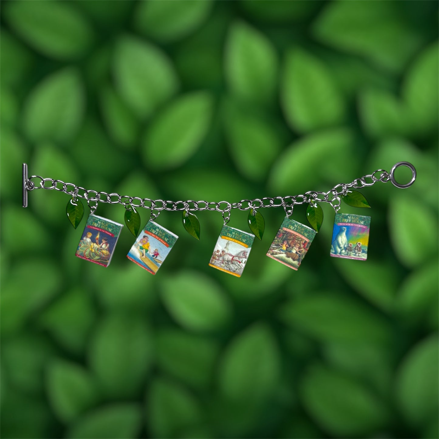 Magic Treehouse miniature book and green leaf charm bracelet on a green leafy background