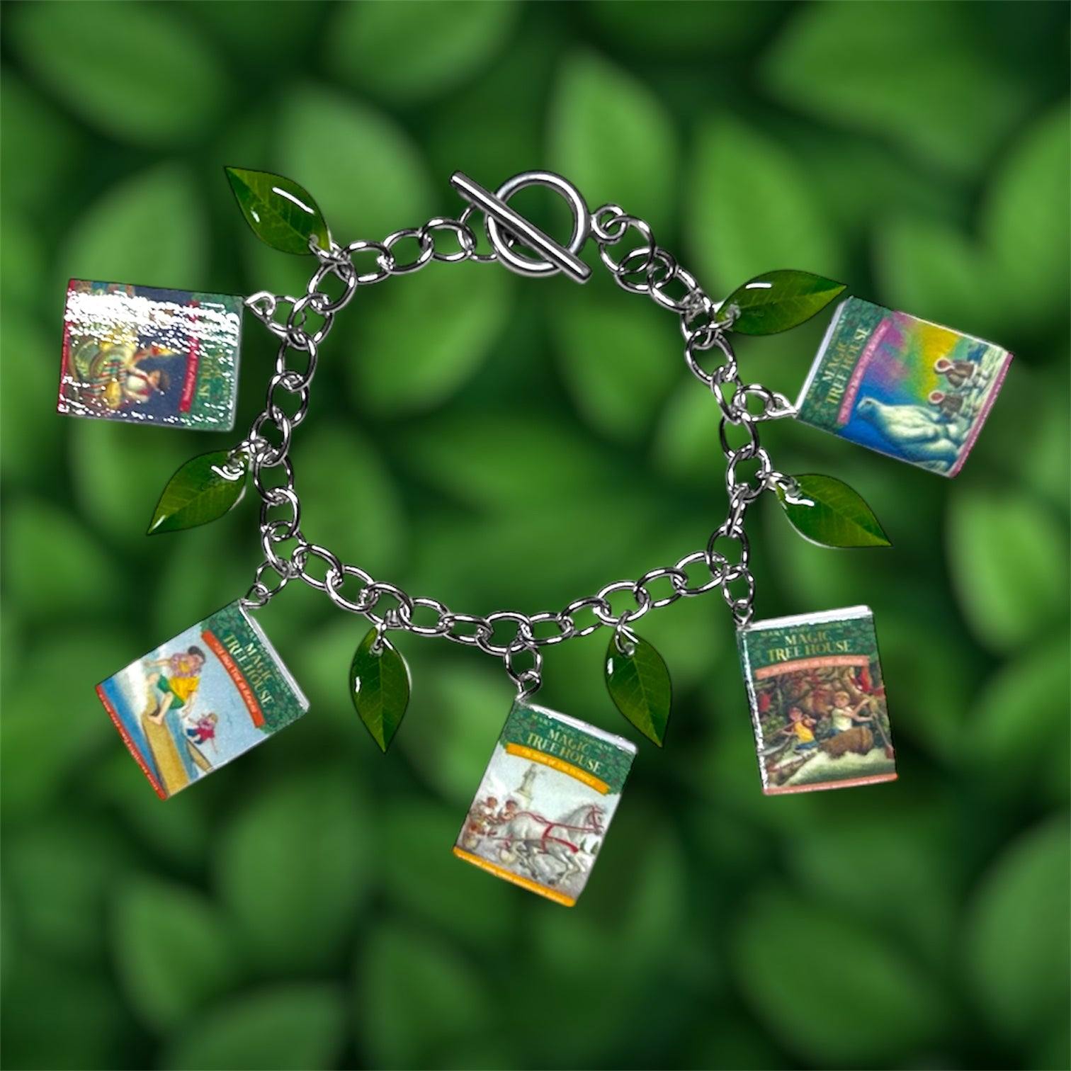 Magic Treehouse miniature book and green leaf charm bracelet on a green leafy background