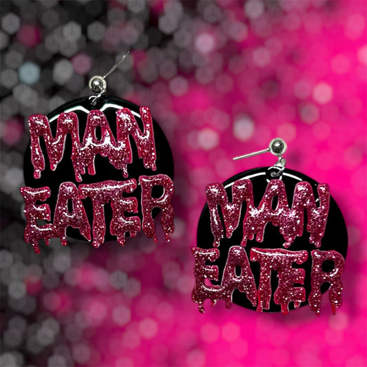 Man Eater drippy glittery resin round dangle earrings on pink and black blurred background