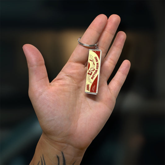 A hand holding an Obsession-inspired One Wish Willow box replica keychain on a blurry backgroud.