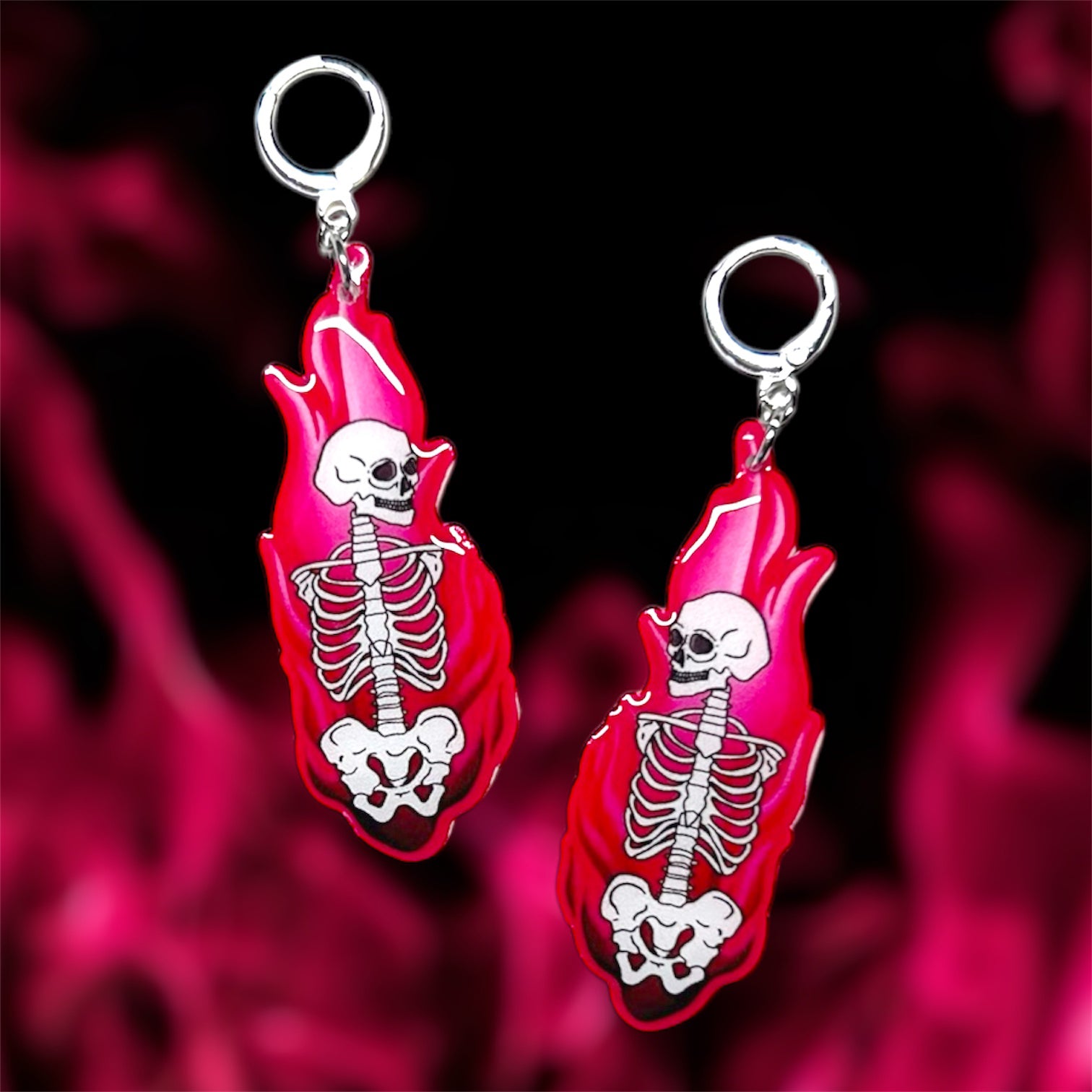 Skeleton in pink fire resin statement earrings on a blurred pink and black background