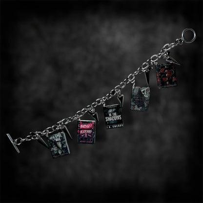 Unfastened smut book charm bracelet on a blurred black distressed background