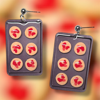Earrings shaped like a cookie tray with red and pink heart Pillsbury Valentine's Day cookies on a colorful background