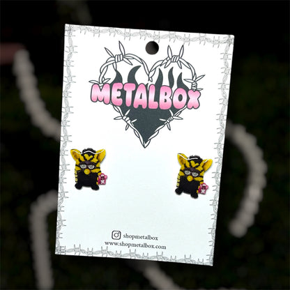Yellow and black striped Furby resin stud earrings on a blurry background